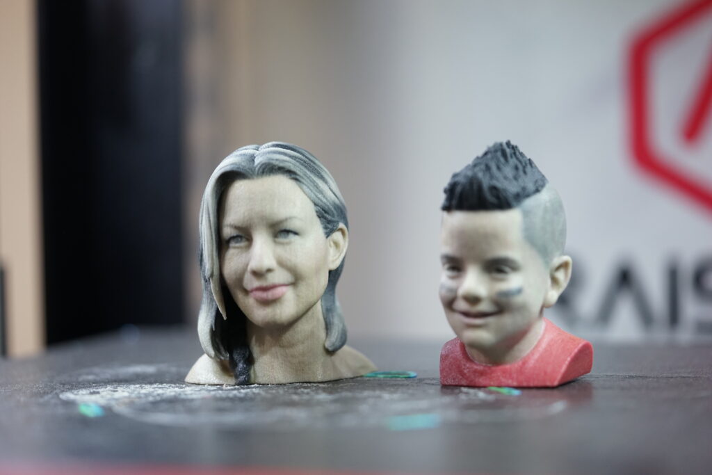 Full-color 3D printed human head bust figurines of a woman and boy, showcasing realistic texture, detail, and color accuracy in sandstone material.