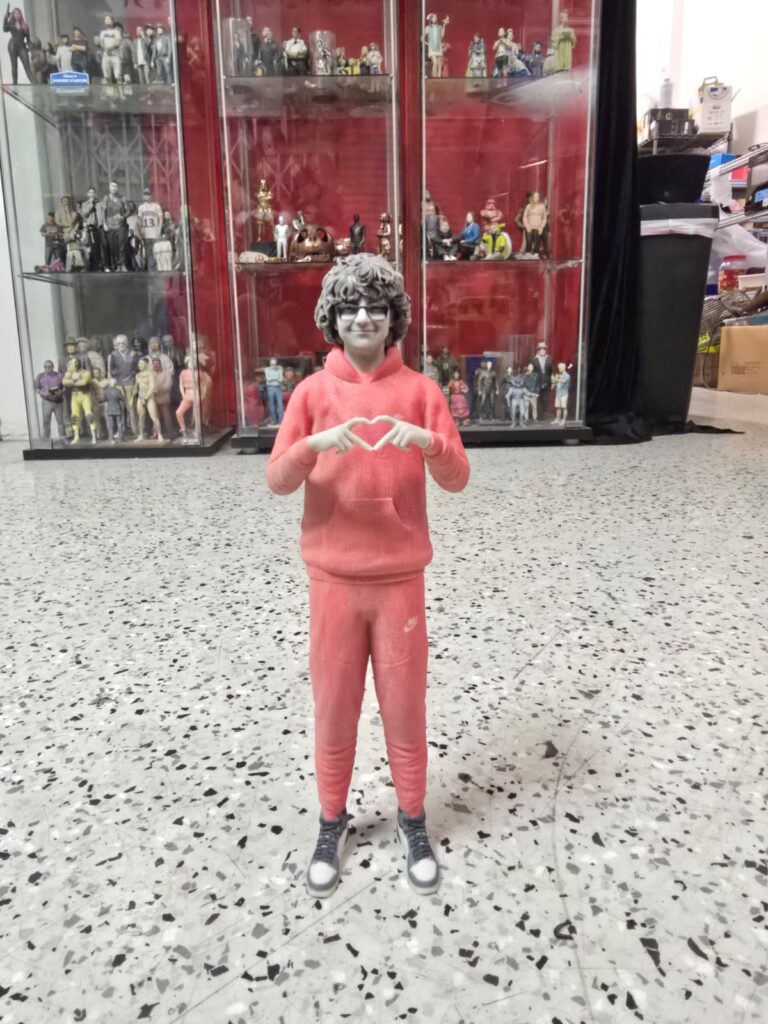 Full-body 3D printed figurine of a boy wearing red clothes, part of a personalized 3D printing gift collection displayed in a showcase.